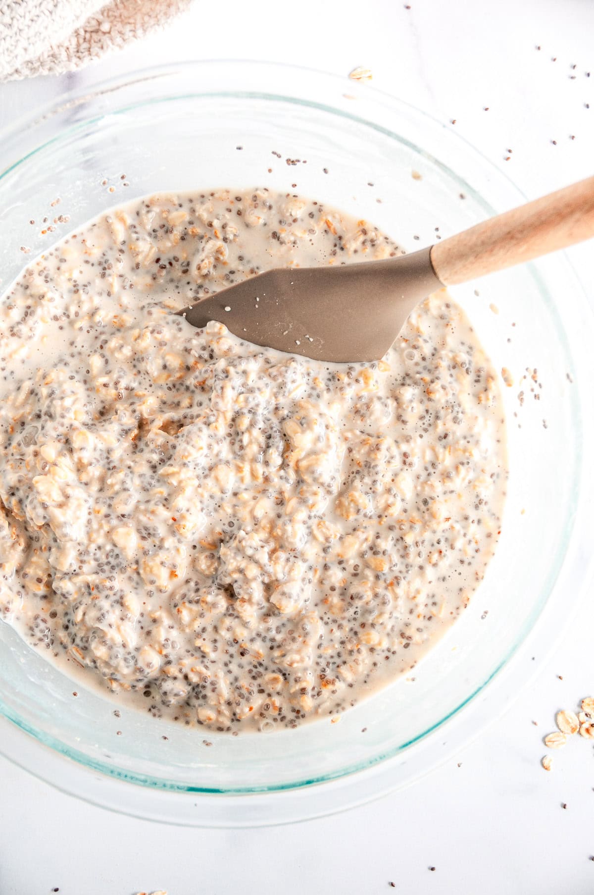 Base recipe ingredients for easy overnight oats mixed together in a glass bowl after resting for 12 hours with gray spoon