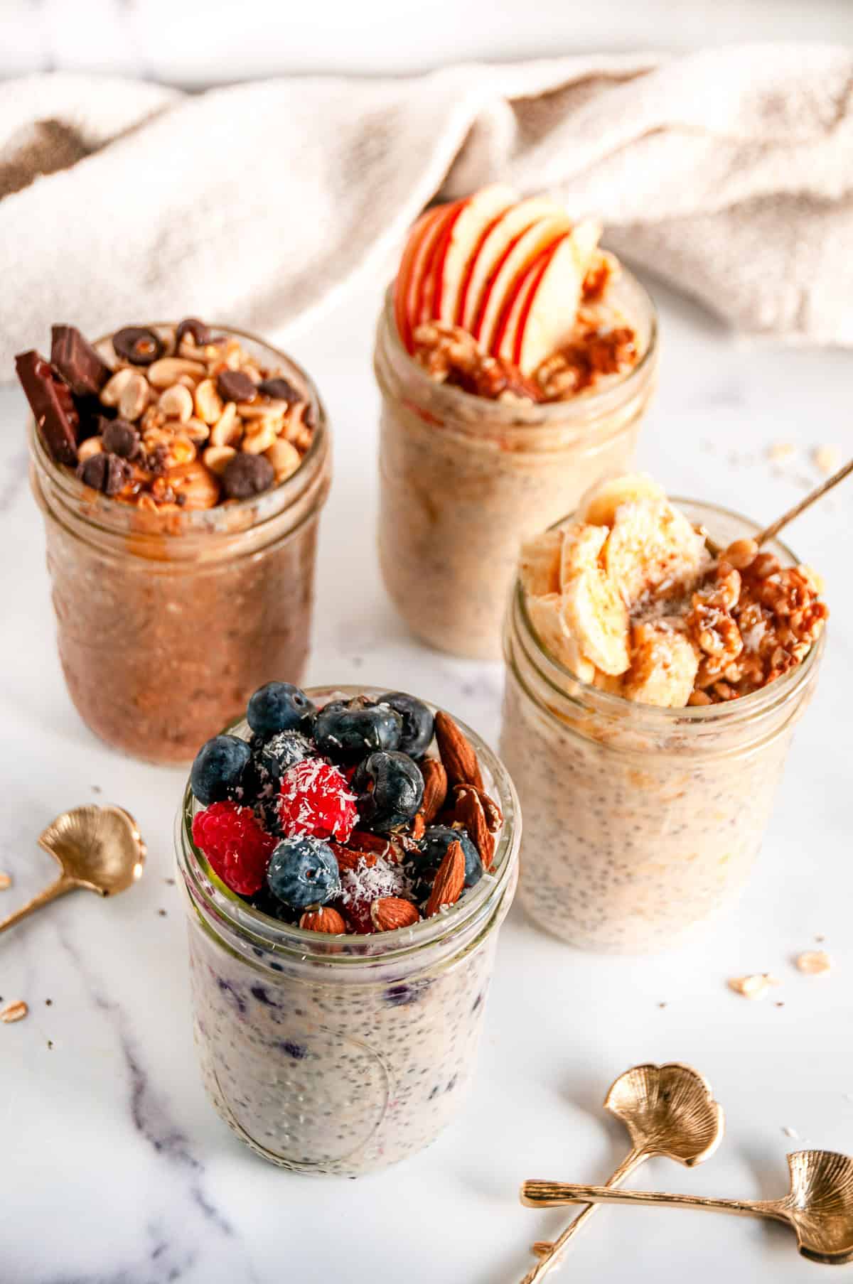 Easy overnight oats meal prep jars with fruit, nuts, and chocolate toppings
