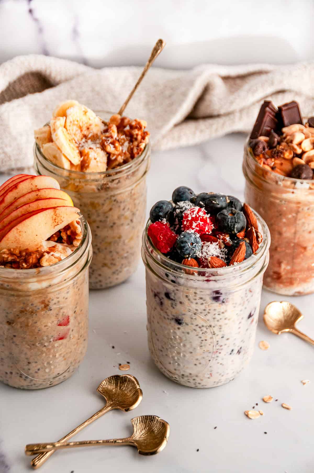 Meal prep jars of easy overnight oats topped with fruit, nuts, and chocolate