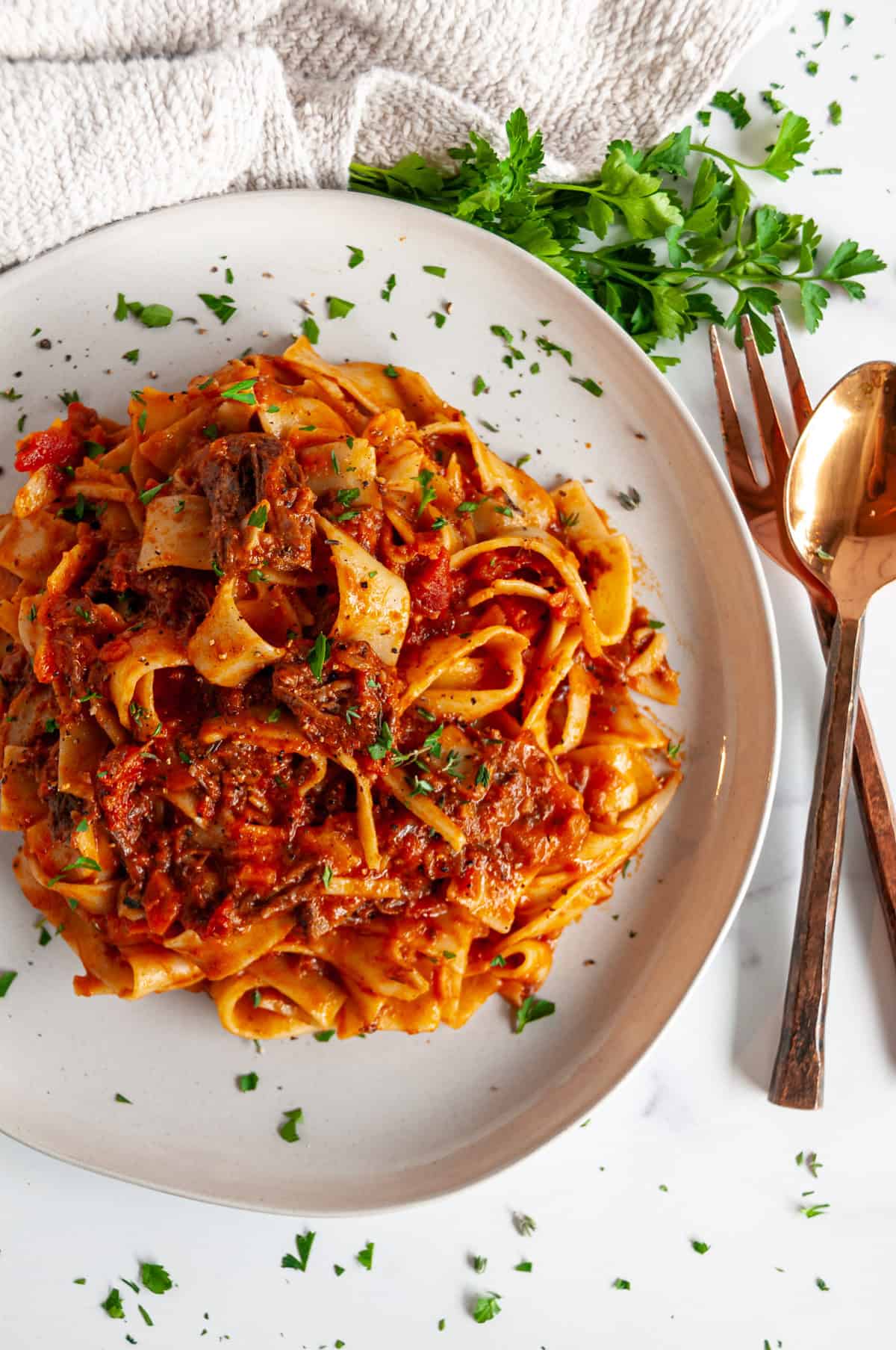 Instant Pot Beef Short Rib Pasta Ragu served over pappardelle with fresh parsley and Parmesan on a white plate overhead.