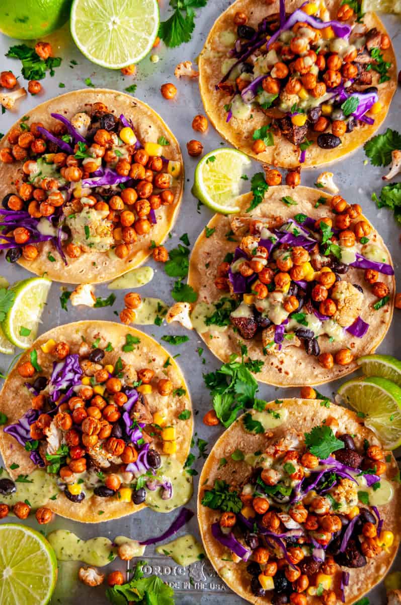 Sheet pan of vegetarian chickpea tacos with roasted chickpeas, veggies, fresh cilantro, and lime wedges.