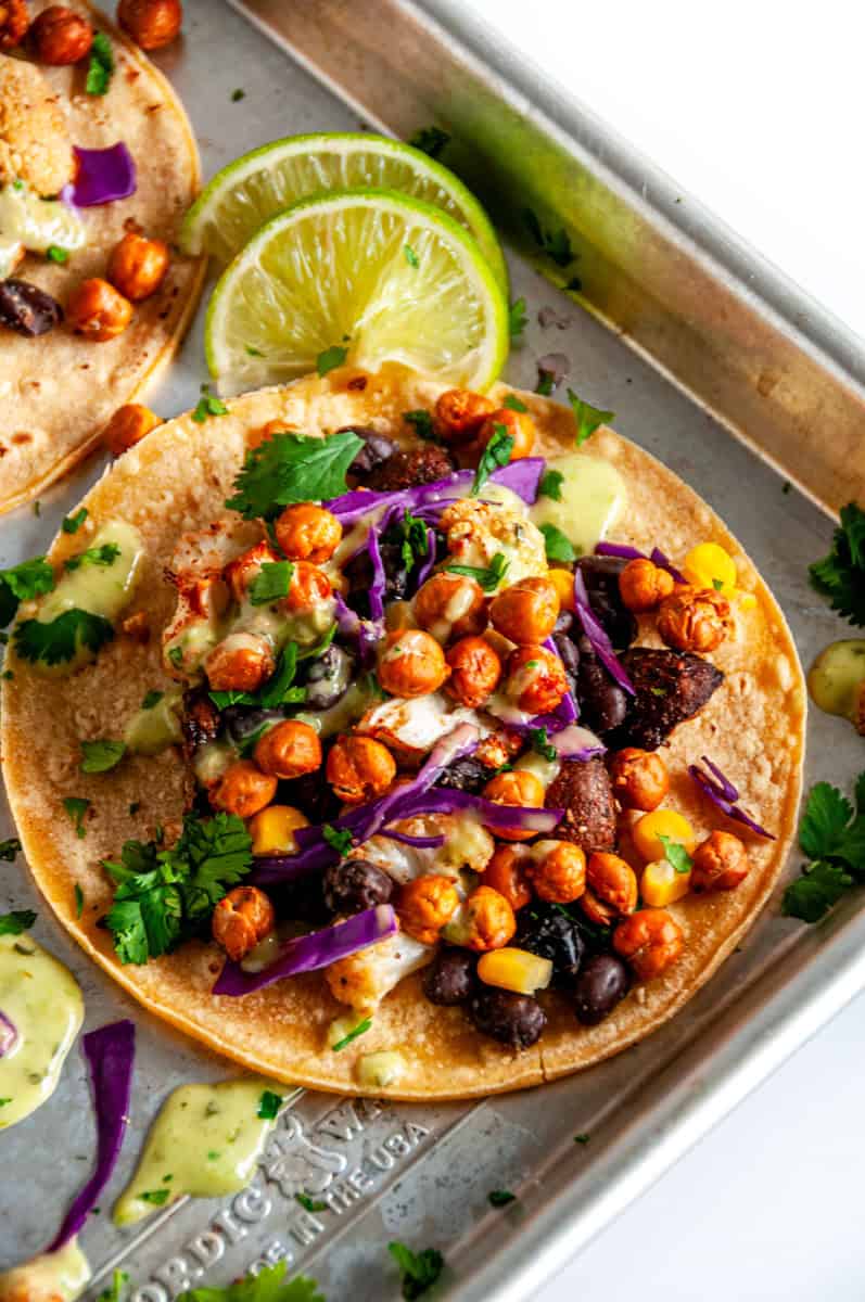Single vegetarian chickpea taco topped with roasted chickpeas, black beans, corn, cauliflower, and green avocado salsa.