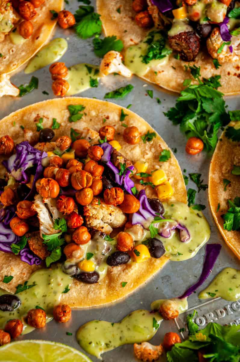 Vegetarian chickpea tacos on a baking sheet garnished with fresh cilantro and lime, ready to serve.