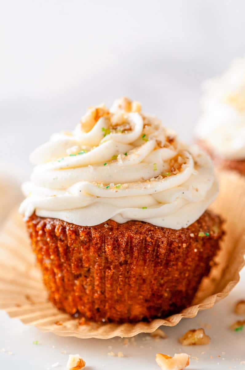 Group of Carrot Cake Cupcakes on cake stand styled with carrot-shaped candies and crumbs