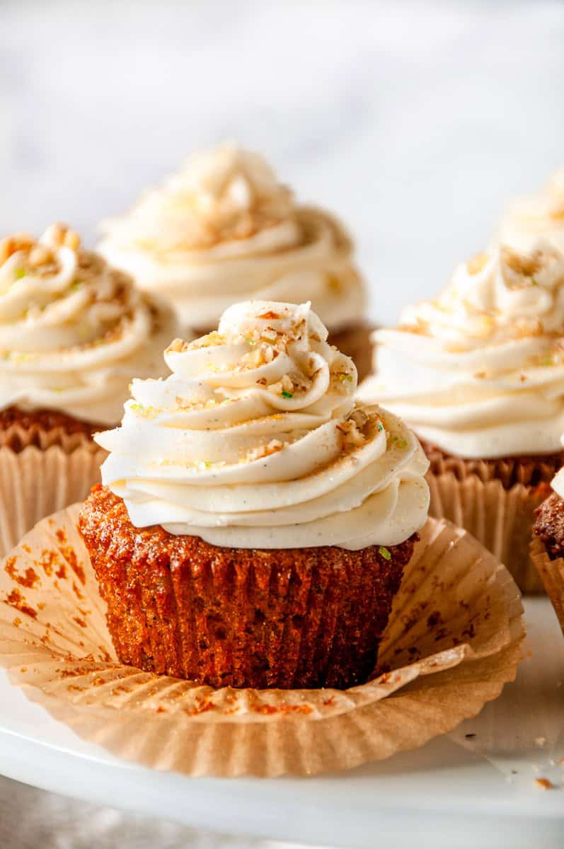 Close up of Carrot Cake Cupcakes with thick cream cheese frosting swirl and chopped nuts on top