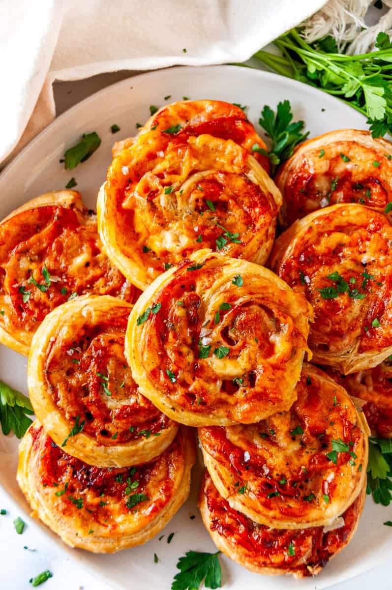 Close-up of ham and cheese pinwheels with melted cheese, layers of ham, and crispy puff pastry spirals