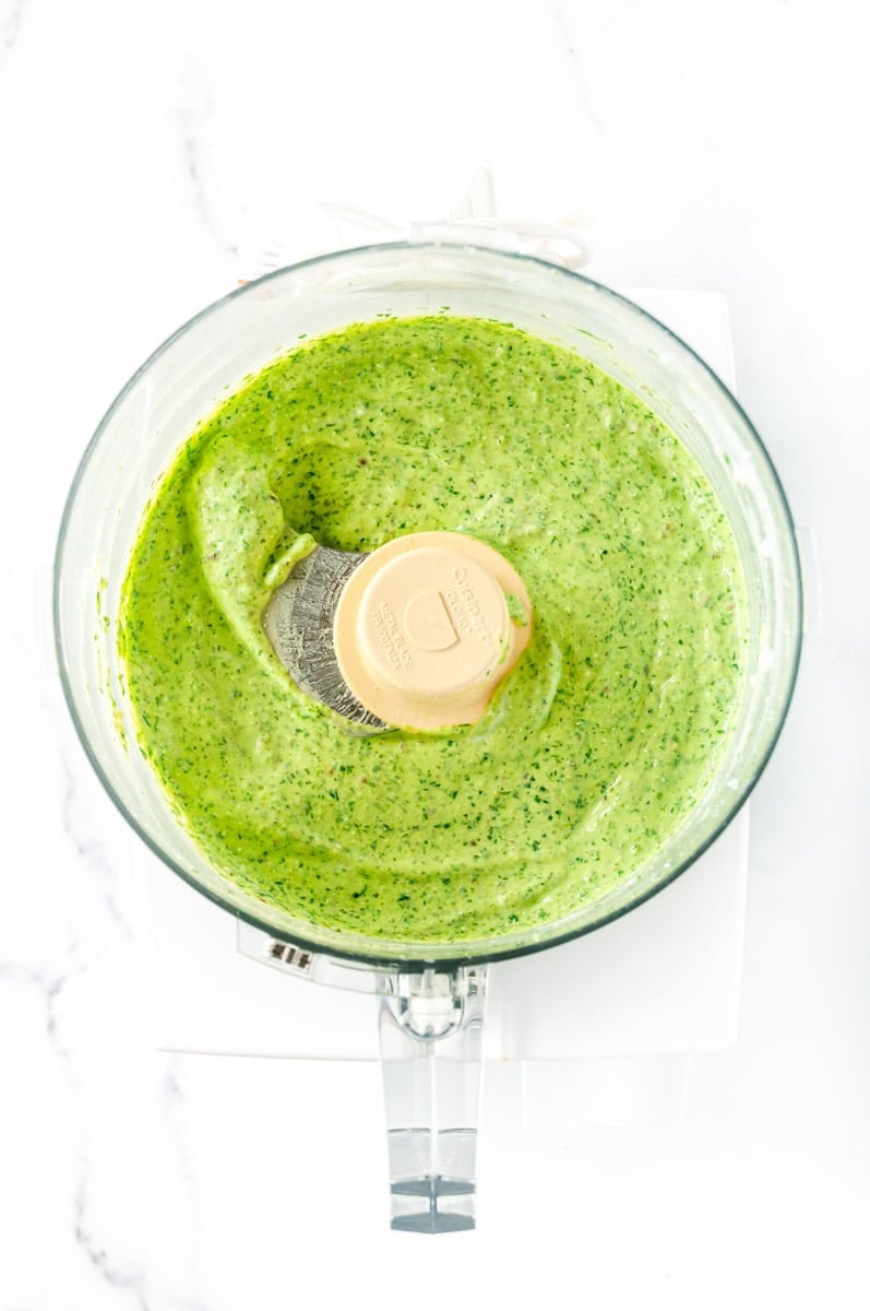 Creamy green goddess dressing freshly blended in a food processor until smooth.